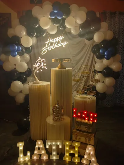 I love how this modern and stylish birthday theme turned out. The decoration features a full balloon arch in black, white, and blue, a personalized neon sign, and marquee letters for the name "LATHA", all arranged neatly with my set of pedestals and props.