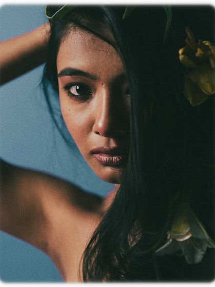 Here, the model's hair is used to create a sense of mystery, covering one side of her face. The direct gaze from her visible eye is powerful and intriguing. The flowers in her hair add a touch of organic beauty to the composition.