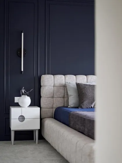 A glimpse into the guest bedroom, where the deep blue walls create a sense of calm and intimacy. The tufted headboard adds a layer of texture and comfort to the space.