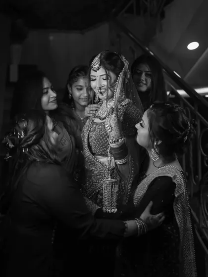 A beautiful black and white photo of the bride surrounded by her bridesmaids. The monochrome tones highlight the emotional connection and the adoring looks of her friends.