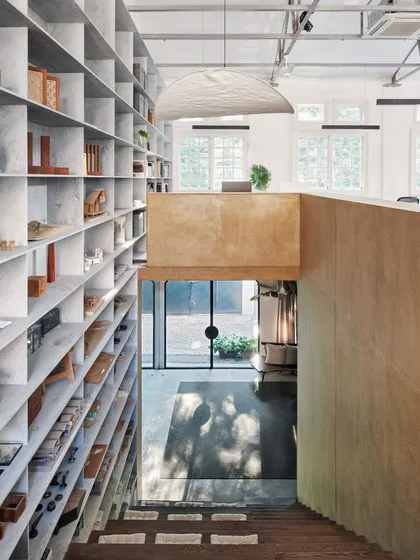 The double-volume space in our studio features a floor-to-ceiling grid of marble shelves. This element is both functional for storage and instrumental in breaking down the scale of the large space.