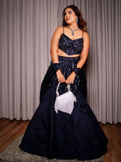 A full view of my brother's engagement look. The navy blue fishtail lehenga creates a beautiful silhouette, while the sequin work adds glamour for an evening event. The look is completed with a matching jewelry set and a contrasting white clutch.