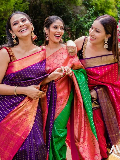 A moment of shared laughter between friends, all looking vibrant and beautiful in our Kanchipuram silk sarees.