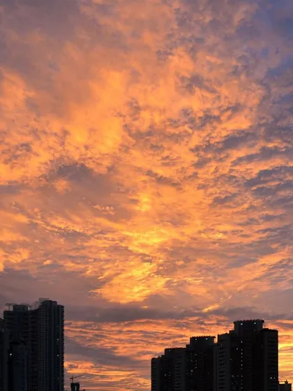 A stunning cloud-filled sky is set ablaze with orange light during a Mumbai sunset, creating a textured and dramatic scene.