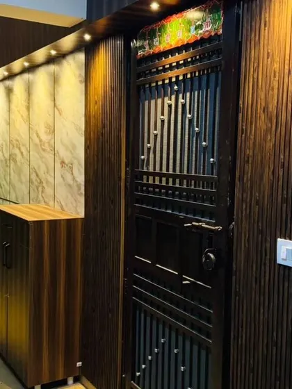 The entrance is critical in Vastu for welcoming positive energy. For this home, I designed a complete entrance solution with dark wood fluted panels, warm overhead lighting, and a practical shoe cabinet to keep the area clutter-free.