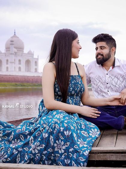 A serene portrait on a boat, capturing a quiet conversation between the couple with the Taj Mahal visible across the water.