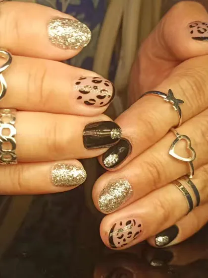 A wild and glamorous design combining leopard print, black polish with zipper details, and full-coverage silver glitter nails.
