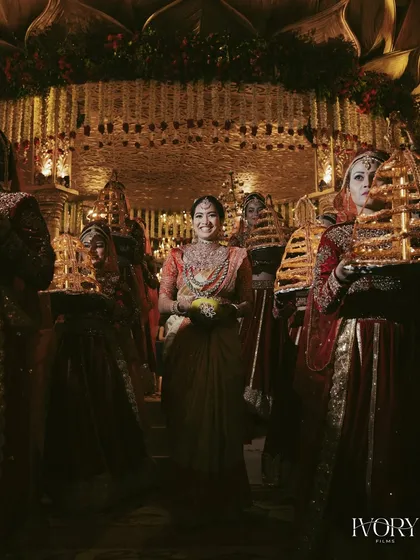 The bride's grand entrance at her South Indian wedding, surrounded by attendants carrying traditional lamps, creating a divine and spectacular visual.