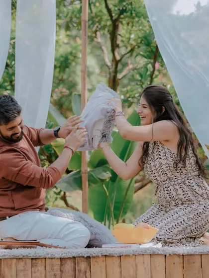 A playful pillow fight during a picnic-style pre-wedding shoot. This fun and energetic activity brings out genuine laughter and creates dynamic, memorable photos that show the couple's lighthearted connection.