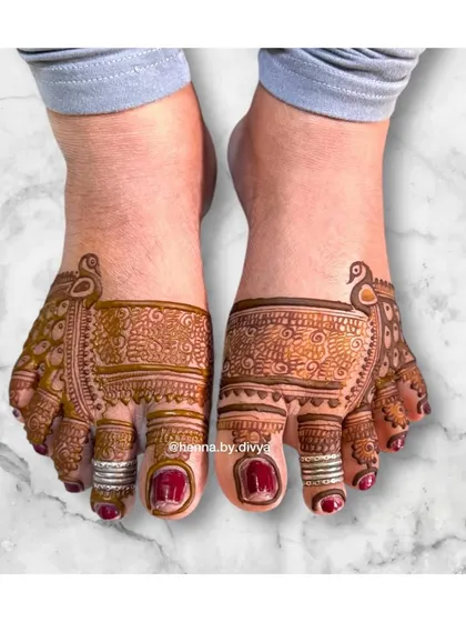 This unique foot design features a peacock motif on the side of the foot, with the pattern extending over the toes. It's a creative placement that looks very graceful.