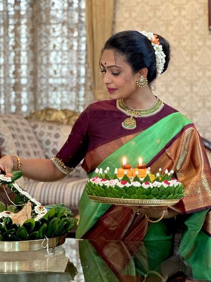 A moment of quiet devotion, lighting a lamp during a festival. The client's green and maroon silk saree is perfect for the occasion.