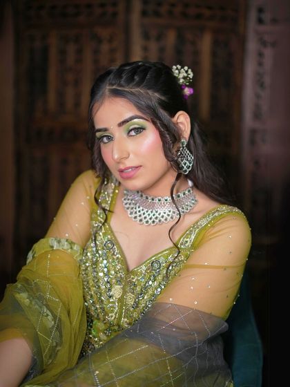 A close-up of the peacock green lehenga. You can see the detailed sequin and beadwork on the blouse and the sheer net sleeves. The matching choker necklace completes the look perfectly.