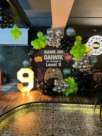 "Game On!" A cool video game themed party for a 9th birthday, featuring a controller prop, a custom backdrop, and a neon green and chrome silver color scheme.