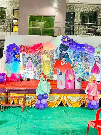 A full view of an outdoor princess-themed birthday party stage. I designed this setup with multiple character cutouts, a shimmering backdrop, and elaborate balloon garlands in pink, purple, and blue to create a magical kingdom for the birthday girl.