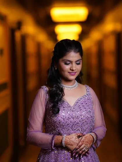 A quiet moment captured. The soft lighting highlights the intricate details of her makeup and the sparkle of her engagement gown.