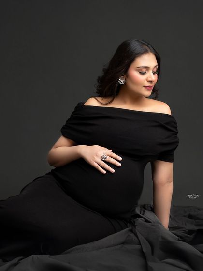 A soft and intimate floor portrait. The draping of the black gown and the gentle pose create a feeling of serenity and peace.