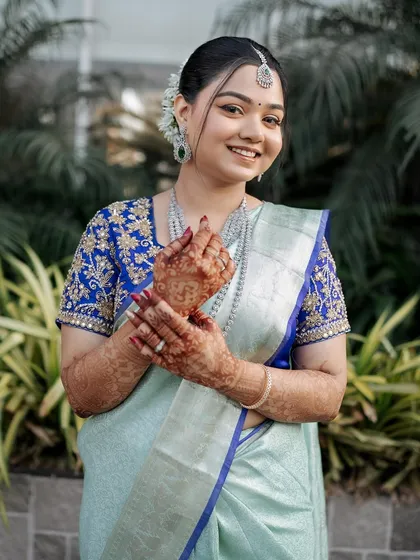 The bride showing off her henna-adorned hands. Her makeup is soft and pretty, letting her natural joy shine through.