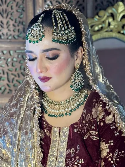 For this Nikkah bride, we chose a traditional Pakistani style with heavy green jewelry. I created a warm, shimmery eye look and a deep berry lip color that matched her maroon velvet dress perfectly.
