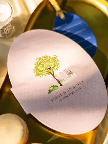 A close-up of an illustrated wedding invitation, capturing the beautiful, soft morning light. The focus on the artwork highlights the bespoke nature of the stationery.