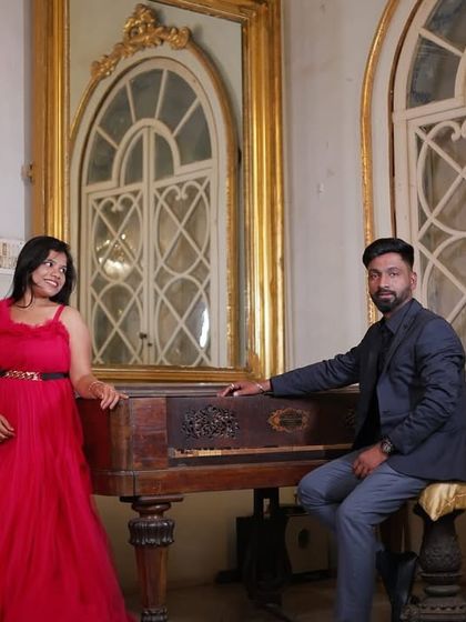 A classic pre-wedding portrait in a vintage setting. The red gown provides a beautiful contrast against the antique piano and ornate mirrors.