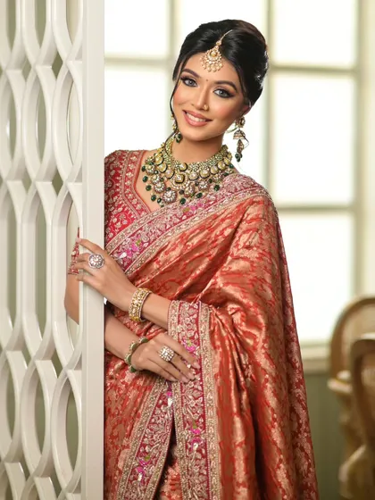 A happy bride peeking through, showcasing the elegant drape of her Banarasi saree.