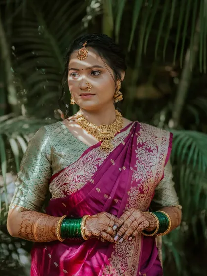 A portrait of traditional beauty. This Marathi bride's look features a soft, glowing base, defined eyes, and a classic hairstyle to complement her rich purple and green saree.