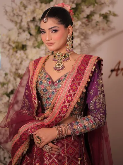 A close-up of the multi-colored silk lehenga. The combination of purple, maroon, and blue embroidery creates a vibrant and festive look.
