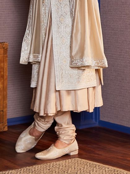 Attention to detail extends to the footwear. The custom-made mojris are embroidered to match the sherwani, ensuring a perfectly coordinated look from head to toe.