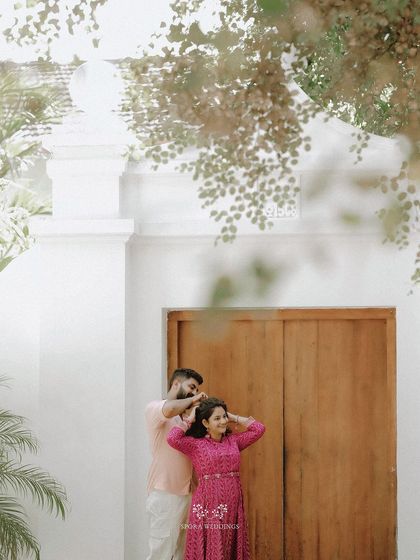 A sweet moment as the groom helps his bride with her hair, framed by beautiful foliage.