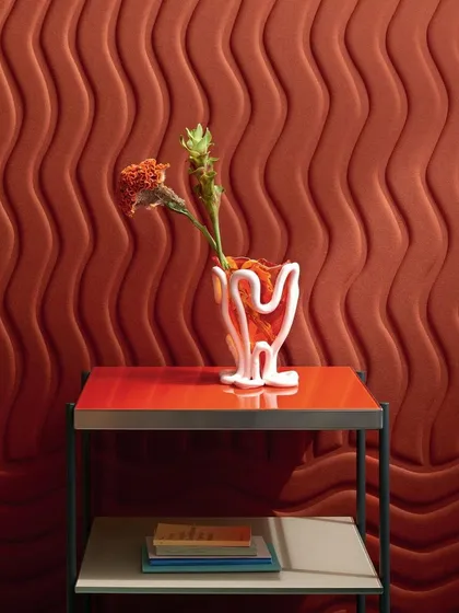 The "Wave Flanelle" design in a rich terracotta color. The sinuous, quilted curves create a striking graphic relief, while the wool material provides excellent acoustic properties for a functional and beautiful wall.