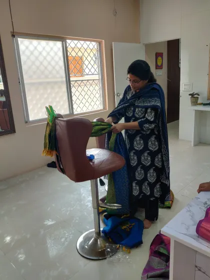 A student practicing how to drape a saree on a salon chair. We use all available tools to learn, making sure you can adapt to any situation you might face with a real client.