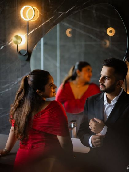 A moody and cinematic portrait in a stylishly lit room. The reflections and warm lighting create a sophisticated and intimate atmosphere, perfect for a glamorous indoor shoot.
