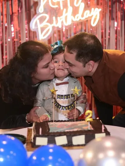 A heartwarming moment where the birthday boy gets kisses from his mom and dad during the cake cutting.
