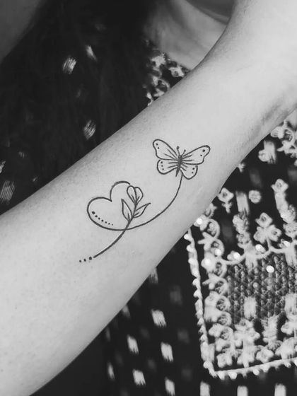 A black and white version of the heart, flower, and butterfly tattoo, highlighting the clean and unbroken line work.