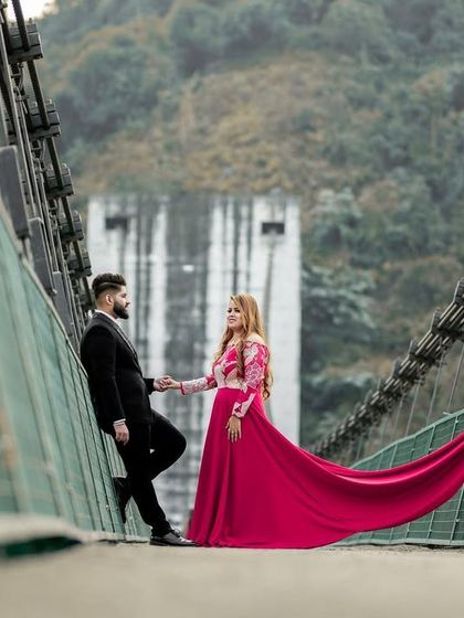 A wide shot on the Dobra Chanti Bridge, using the bridge's architecture to frame the couple and the bride's stunning red gown.