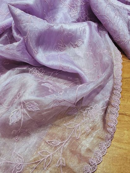 A crush tissue saree in a pastel lavender shade with fine, self-colored floral embroidery. The scalloped border adds a beautiful finishing touch to this ethereal piece.