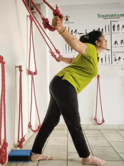 Another variation using the wall ropes, this time with a wider stance to stretch the sides of the body and the hamstrings. This is part of our holistic approach to relieving pain by working on the entire body's alignment.