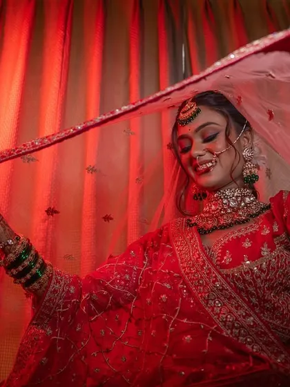 A beautiful, joyful portrait of the bride under her veil, captured with dramatic red lighting.