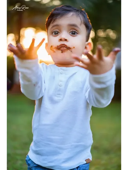 Look at my hands. This is the pure, unscripted joy of a second birthday chocolate cake smash. Ivaan shows off his messy hands against the warm sunset light, creating a perfect candid memory.