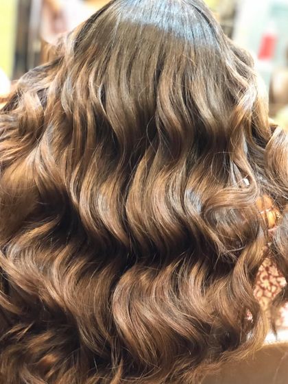 A closer look at the caramel balayage, showing the detail and blend of the color. The waves help to catch the light, making the different tones stand out beautifully.