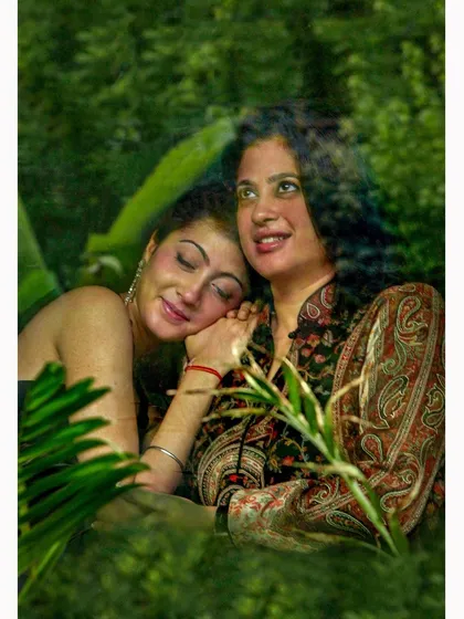 A creative family portrait of a mother and daughter, viewed through a window to create a soft, reflective effect. This technique adds an artistic layer to the image, enhancing the feeling of warmth and tenderness.