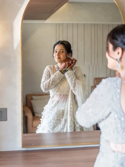 A final touch-up in the mirror. This getting-ready portrait captures the anticipation and excitement of the bride on her wedding day.