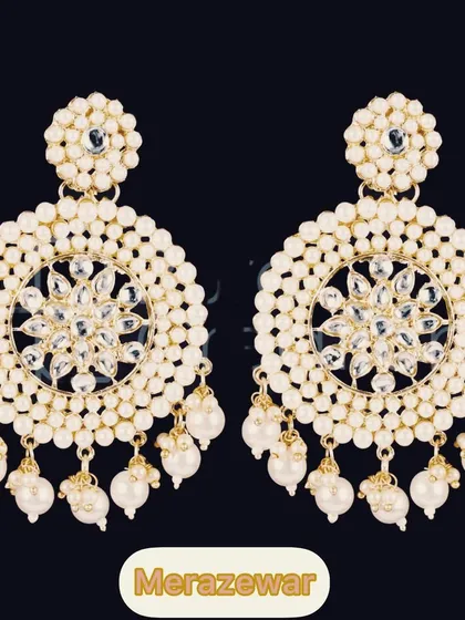 A classic and elegant choice. These large circular chandbalis are detailed with kundan work and surrounded by pearls, making them a timeless piece for any ethnic wardrobe.