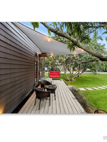 The wooden deck of a prefab home, complete with a cozy seating area and string lights. This shot captures the essence of relaxed outdoor living and the simple comforts of a modern cottage.