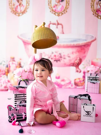 A happy baby surrounded by pink shopping bags and spa accessories.