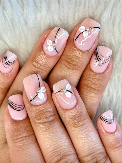 Soft, subtle, and oh-so-stylish. These blush-toned nails feature delicate 3D florals with pearl accents and fine black line art for a poetic and graceful look.