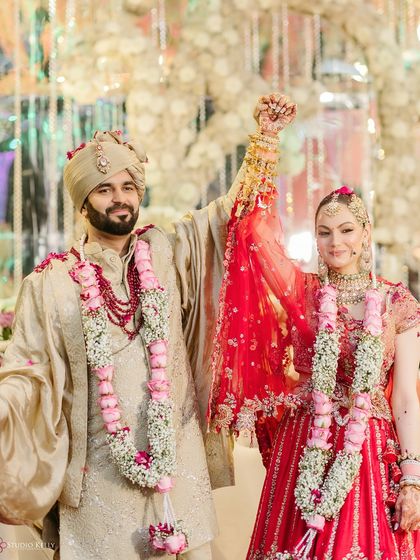 The couple celebrates their union with hands raised high after the Varmala ceremony, a moment of pure triumph and joy.