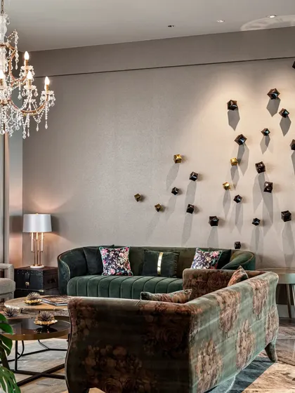 This wall features a sofa upholstered in a stunning Sabyasachi print, balanced by another in solid green. The scattered metal cubes on the wall were planned from the start to ensure the home feels complete and curated without being cluttered.