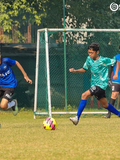 A GSC player dribbles towards the goal, with a KOTA FC player in pursuit.