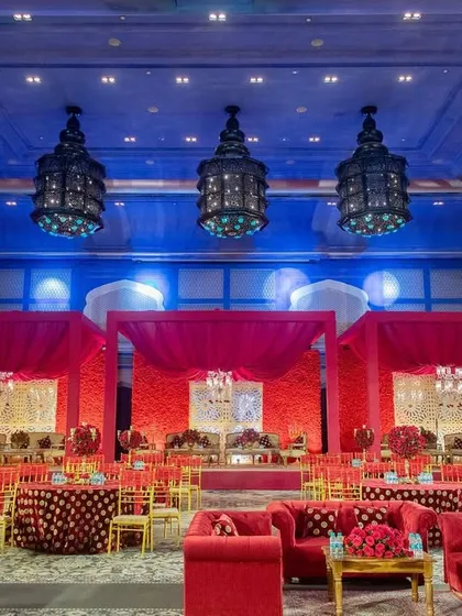 A wide view of the grand ballroom at Fairmont Jaipur, transformed with a dramatic red and blue color scheme for a royal wedding reception.